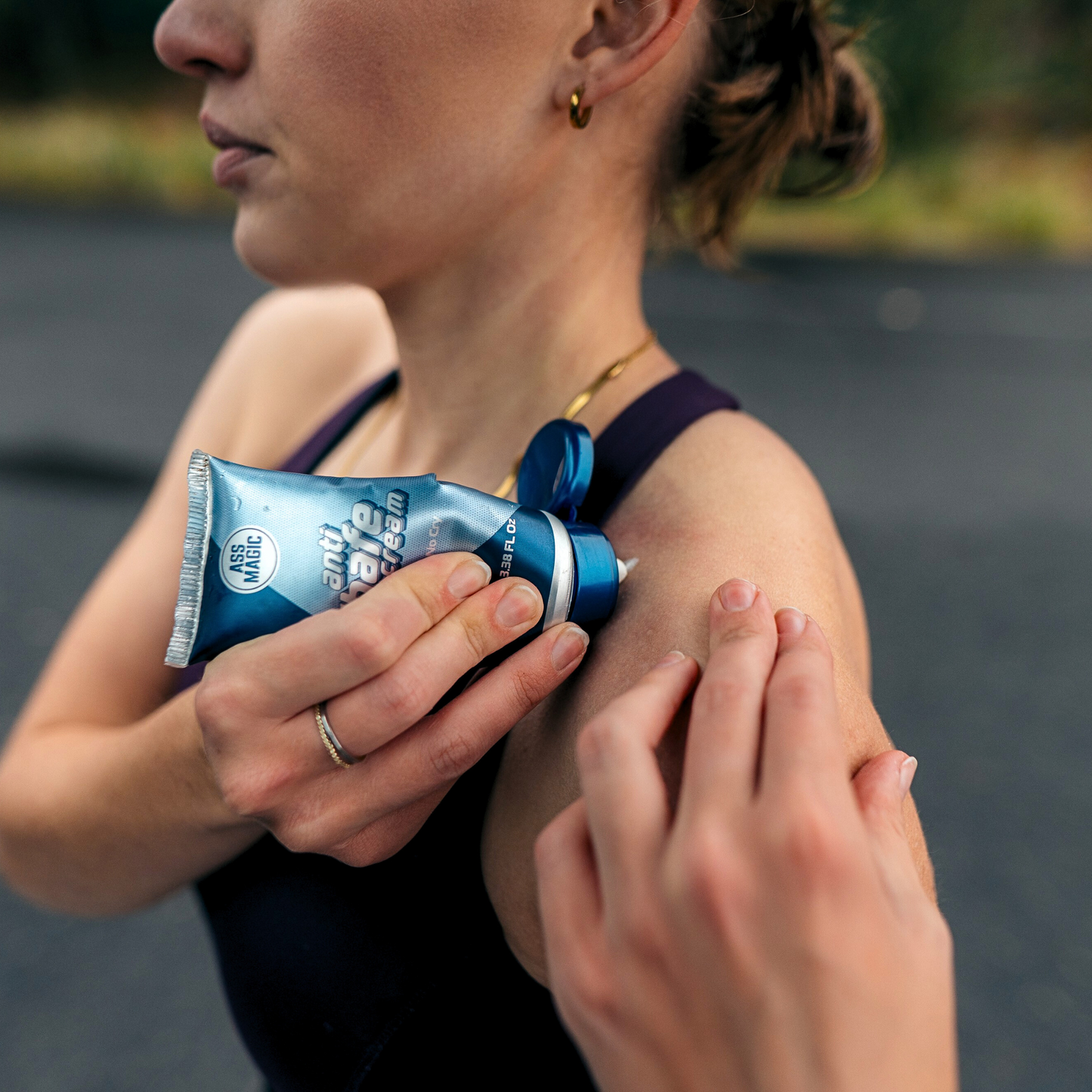 ASS MAGIC Anti Chafe Balm being applied to a female's shoulder area underneath the bra-strap to avoid bra-strap chafing.