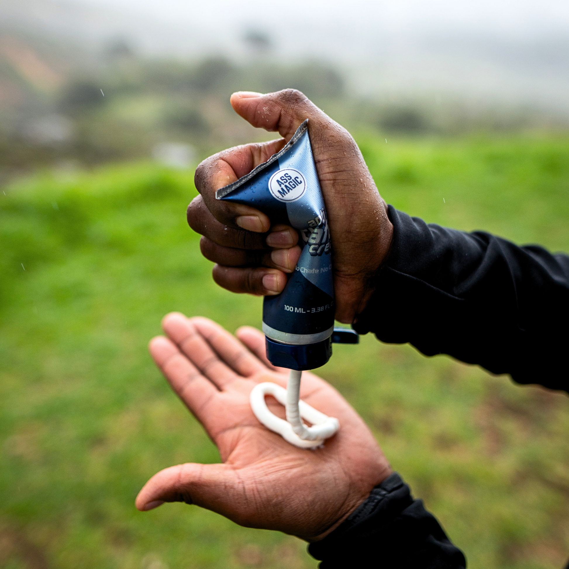 A person squeezing ASS MAGIC anti-chafe cream into their palm before outdoor activity, highlighting protection against running chafe and skin irritation.