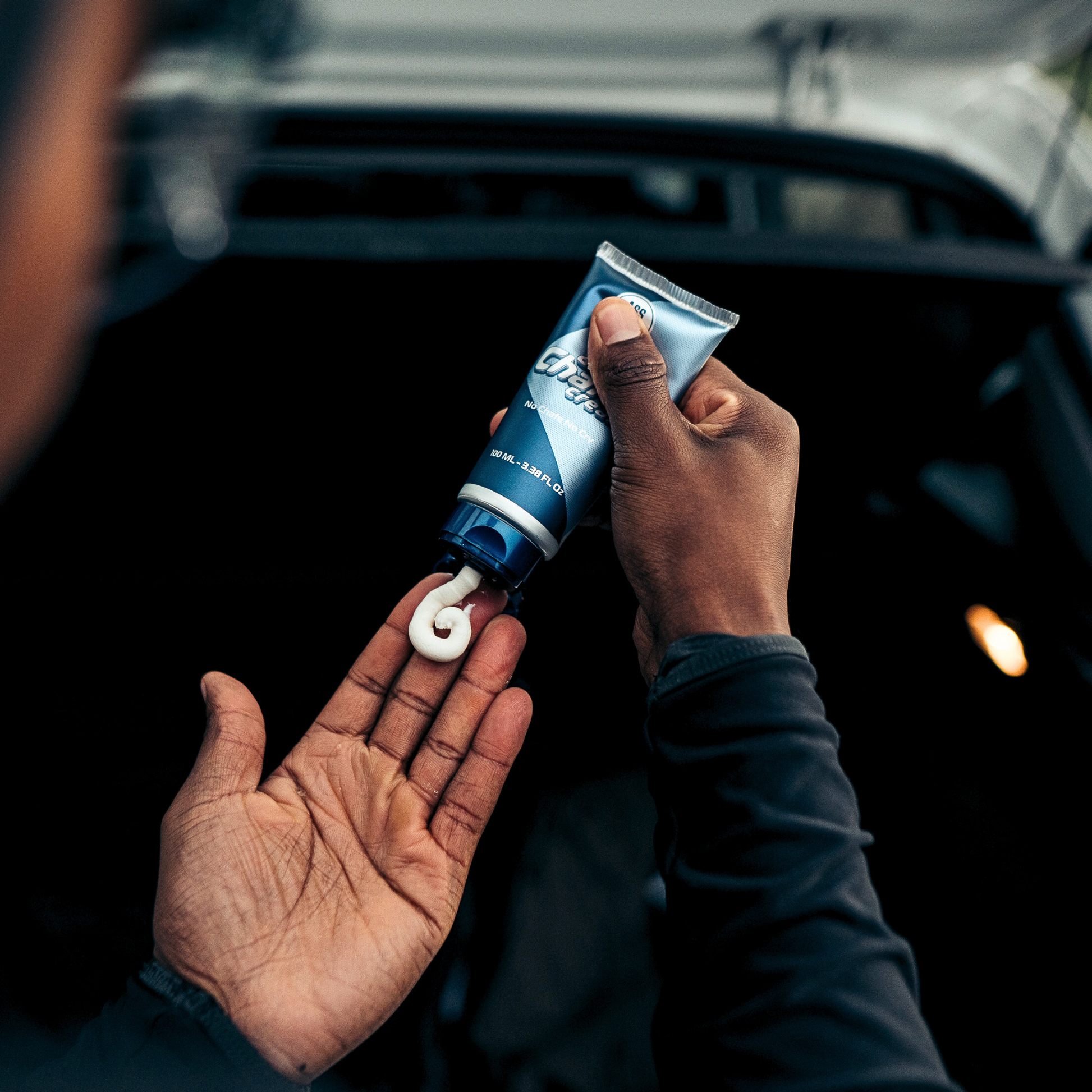 Athlete dispensing ASS MAGIC anti-chafe cream from a tube into their hand, ready for use as part of a sports skincare routine. Detail on cream texture.