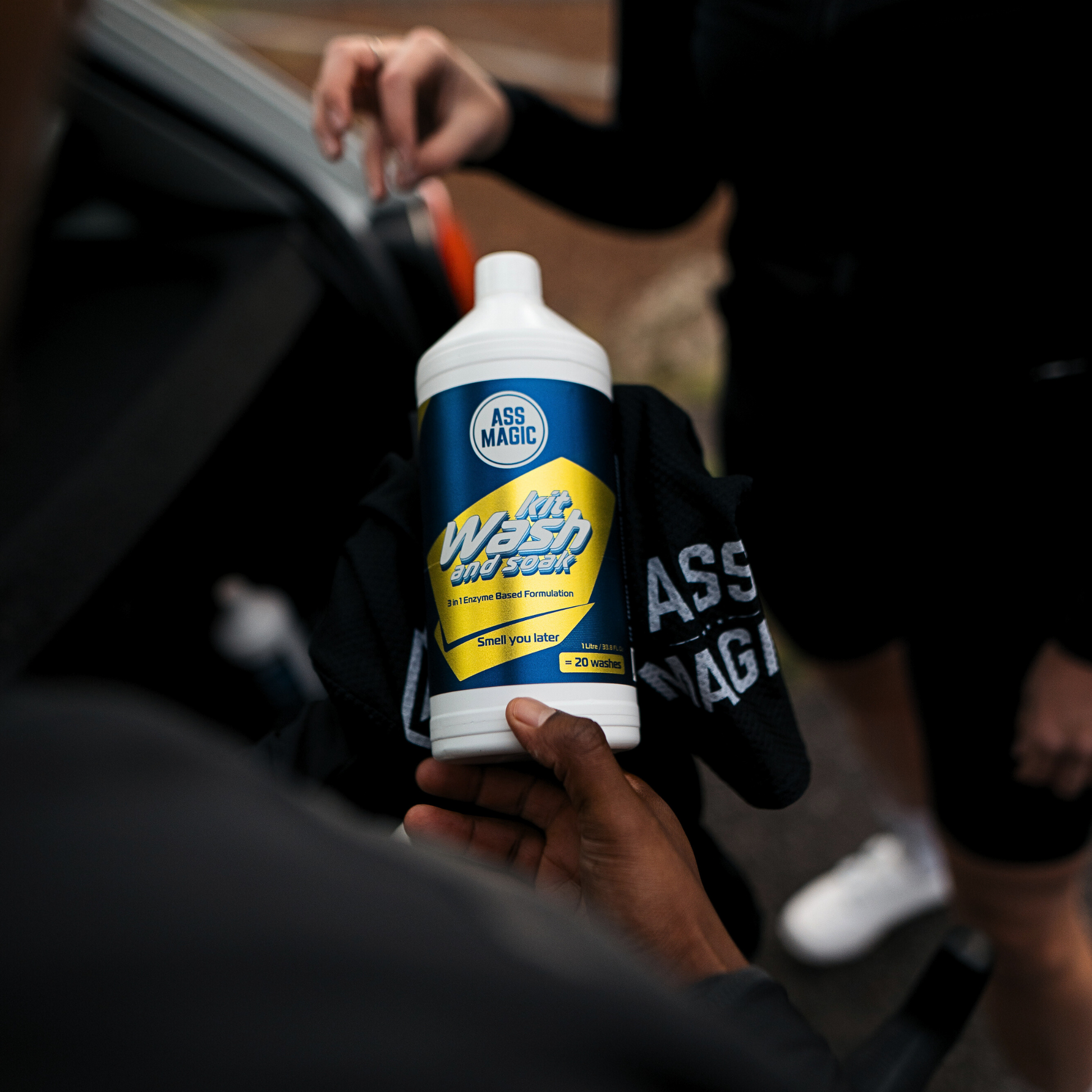 Athlete holding ASS MAGIC 1L Kit Wash and Soak bottle, ideal for cleaning technical gear and sports kit fabrics post-training.